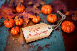 Happy Thanksgiving on wooden tag with pumpkins and leaves